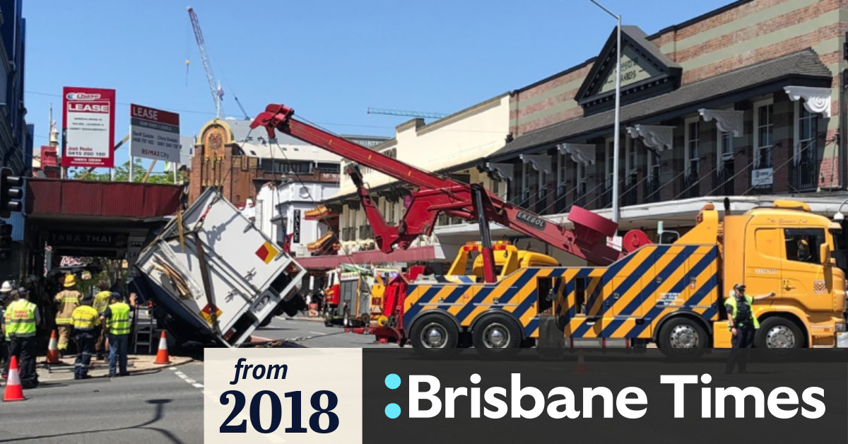 Truck smashes traffic lights, leans on side at Brisbane intersection